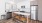 Tracy CA Apartments for Rent - The Vela - Modern Kitchen with Stainless Steel Appliances, White Quartz Countertops, White Cabinetry, a Cooking Island with Stool Seating, and Wood-Style Flooring