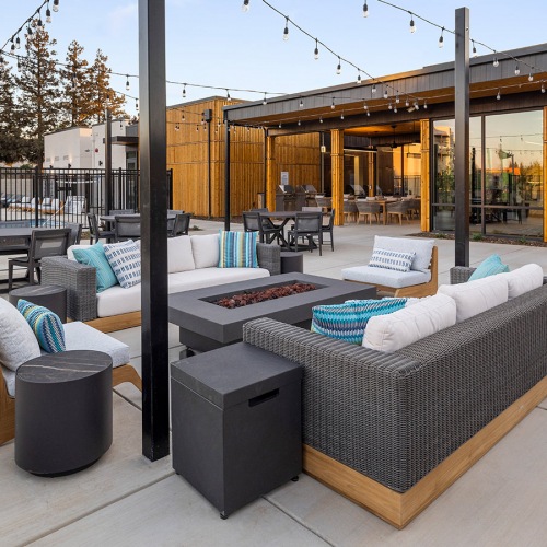 Firepit Apartments for Rent in Tracy, CA - The Vela - Relaxing Outdoor Lounge with Fire Pit, Cozy Seating, String Lights, and Pool Views